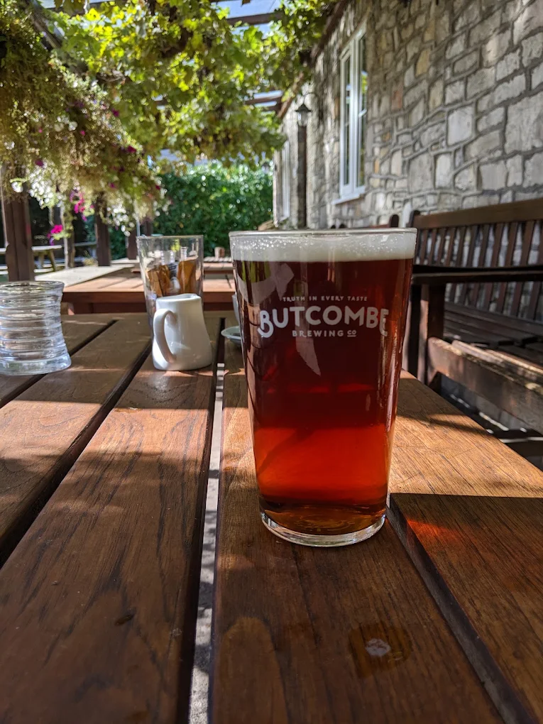 A pint of Butcombe on a sunlit garden table beneath the flowering veranda