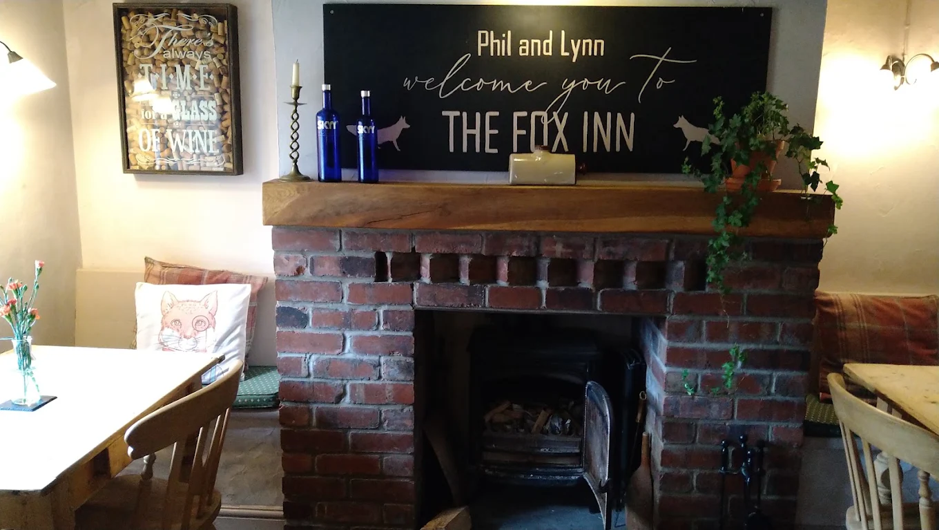 The brick fireplace and wood burner beneath the Fox Inn welcome sign