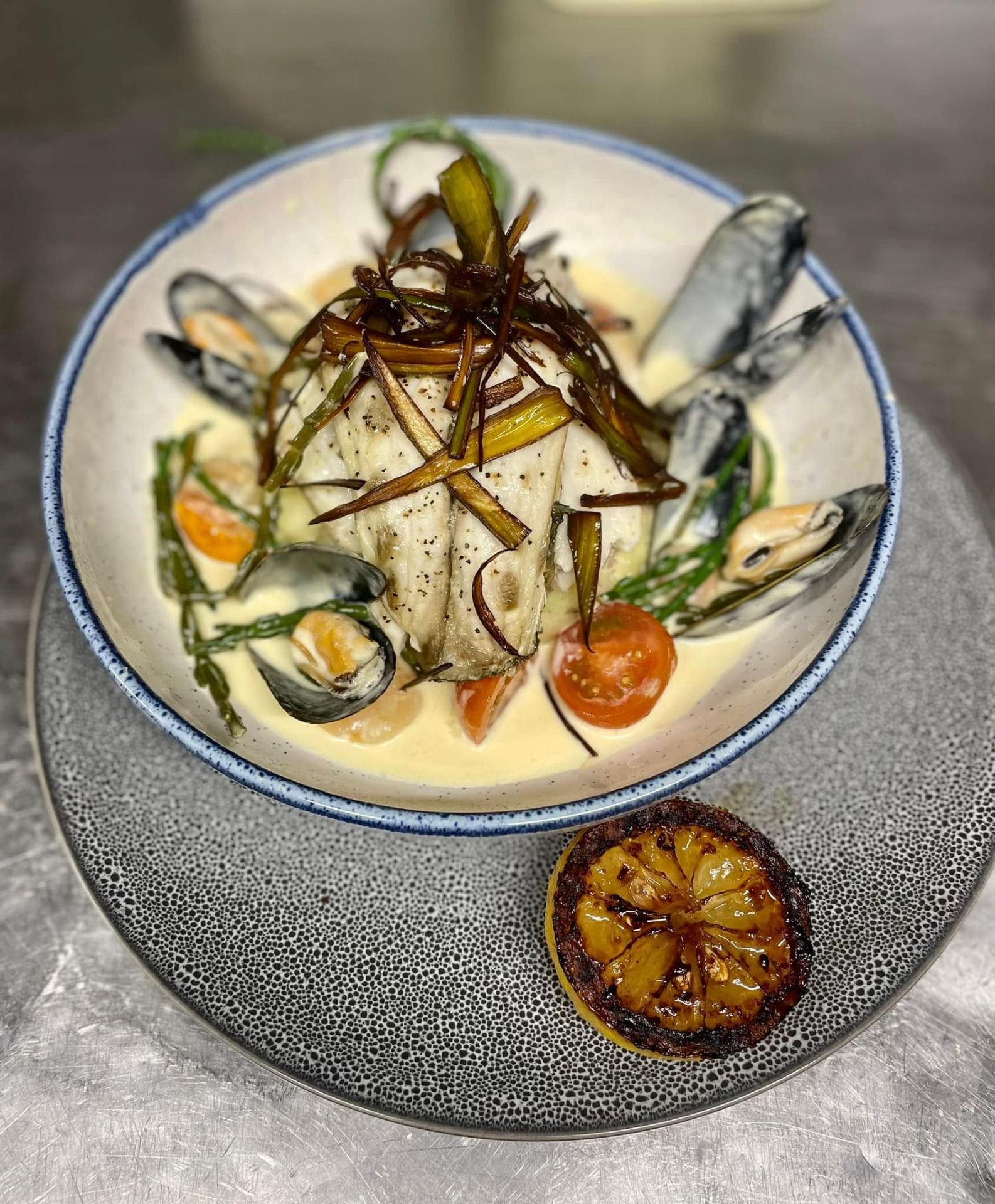 A fish fillet with mussels and samphire in a creamy sauce