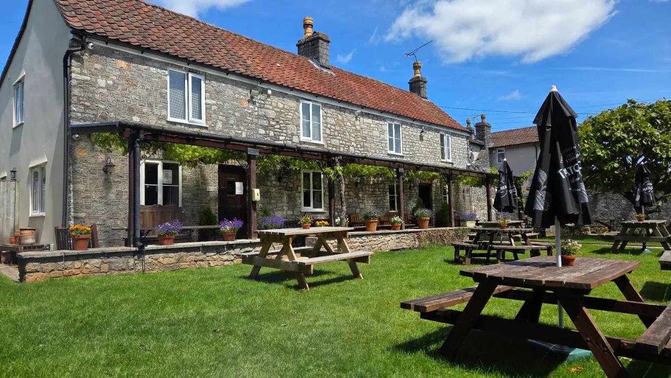 The stone frontage of The Fox Inn seen across the lawn and picnic tables